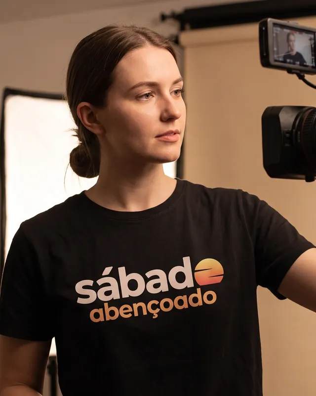 Integrante da equipe ajustando a câmera, de camiseta preta com o logo na versão 4